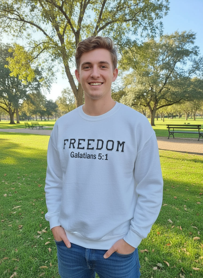 Man wearing a white sweatshirt with 'FREEDOM Galatians 5:1' text, standing outdoors.